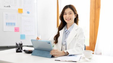 Çalışmak için dizüstü bilgisayar kullanan iş kadını, ofiste çalışan Asyalı kadın, evrak ve ekipmanlarla çalışan muhasebeci, mali işlemler için tablet kullanan.