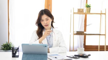 Çalışmak için dizüstü bilgisayar kullanan iş kadını, ofiste çalışan Asyalı kadın, evrak ve ekipmanlarla çalışan muhasebeci, mali işlemler için tablet kullanan.