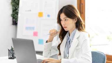 Çalışmak için dizüstü bilgisayar kullanan bir iş kadını, ofiste çalışan Asyalı bir kadın, evrak ve ekipmanlı bir muhasebeci, finansal işlemler için bilgisayarları kullanan bir muhasebeci..