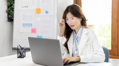 Çalışmak için dizüstü bilgisayar kullanan bir iş kadını, ofiste çalışan Asyalı bir kadın, evrak ve ekipmanlı bir muhasebeci, finansal işlemler için bilgisayarları kullanan bir muhasebeci..