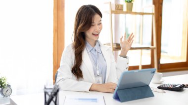 Çalışmak için dizüstü bilgisayar kullanan iş kadını, ofiste çalışan Asyalı kadın, evrak ve ekipmanlarla çalışan muhasebeci, mali işlemler için tablet kullanan.