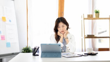 Çalışmak için dizüstü bilgisayar kullanan iş kadını, ofiste çalışan Asyalı kadın, evrak ve ekipmanlarla çalışan muhasebeci, mali işlemler için tablet kullanan.