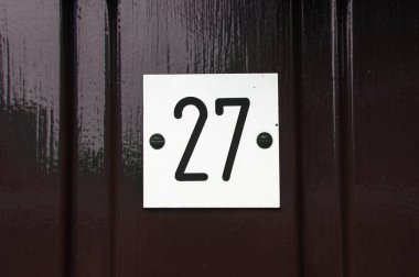 Beyaz plastik bir plakaya işlenmiş 27 numaralı siyah ev.