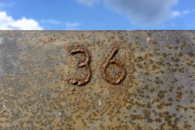 36 numaralı ev metal bir arka planda kaynak yapılmış, paslı.