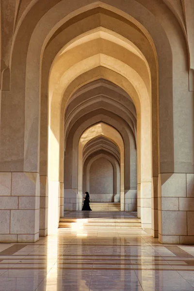 Muslim woman walking through arches