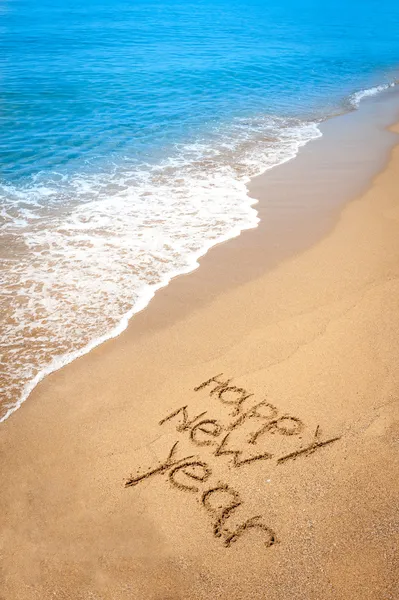 Feliz año nuevo escrito en arena en la playa tropical —  Fotos de Stock