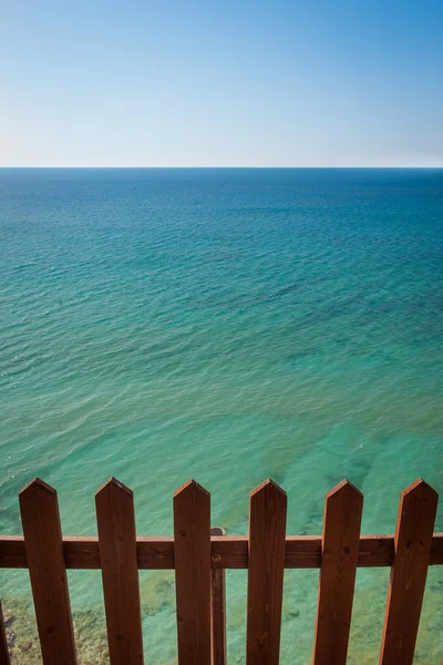 Houten hek voor prachtige turquoise en kalme zee op cor — Stockfoto