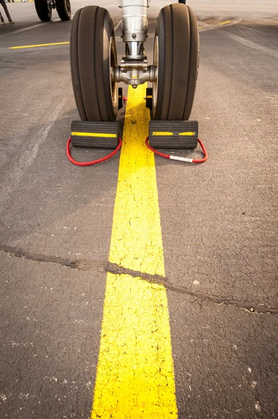 Airplane tires on yellow line — Stock Photo, Image