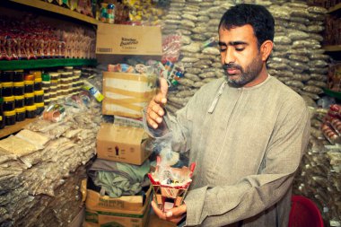Incense man burning myrrh (mira) on market, suk, in Muscat, Oman clipart