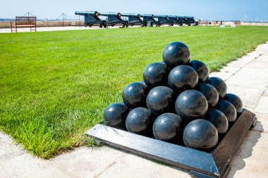 Old cannonballs stacked in pyramid, in front of cannons, on Valletta Castle, Malta clipart