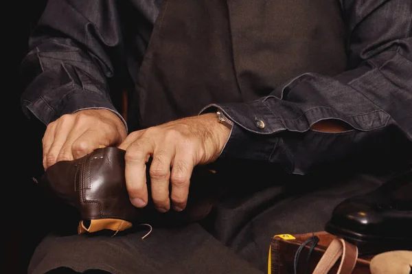 Shoemaker tools. Shoemaker\'s workshop. A seated shoemaker sews shoes. Selective focus.