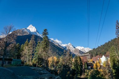 Bir sonbahar günü, yüksek karlı dağların arasında küçük bir turist köyünde yürümek.