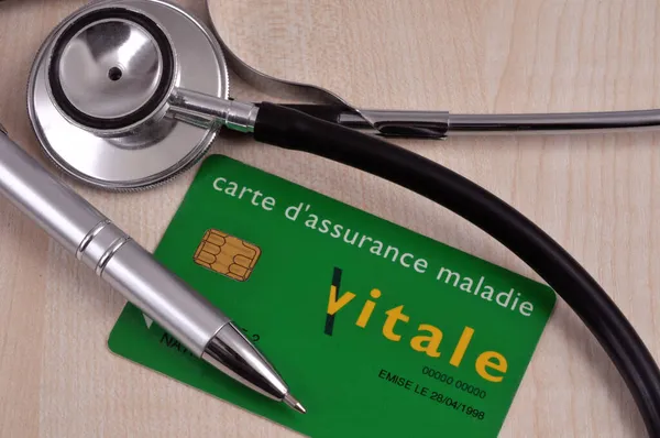 聴診器とペンの横に横たわるフランスの健康保険カード — ストック写真