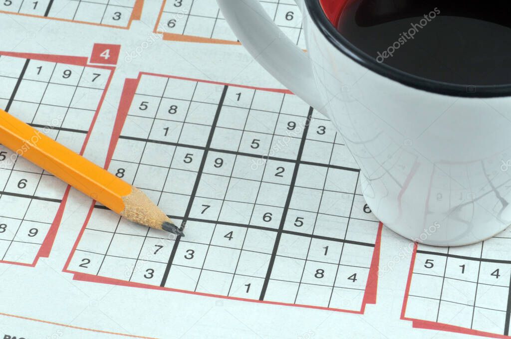 Close up on sudoku puzzles with pencil and cup of coffee 