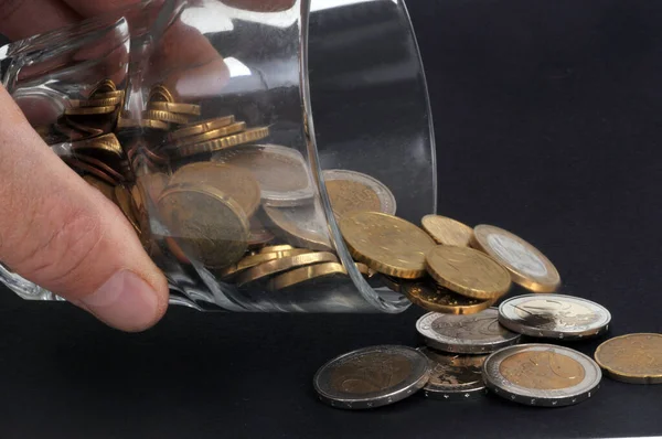 黒い背景にコインのガラスがこぼれている水の支出の概念 — ストック写真
