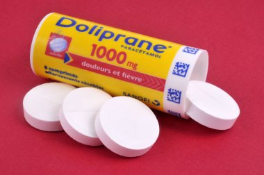 Dolgun Doliprane tabletlerinden oluşan bir tüp kırmızı arkaplanda açıldı.