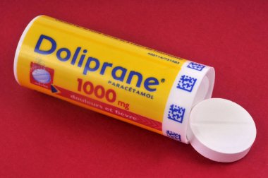 Dolgun Doliprane tabletlerinden oluşan bir tüp kırmızı arkaplanda açıldı.