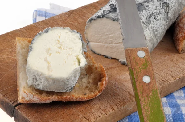 用刀和面包特写切割板上灰蒙蒙的山羊奶酪原木 — 图库照片