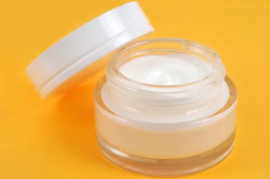 Sarı arkaplanda yakın plan nemlendirici kavanozu açıldı 