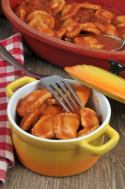 Ravioli güveci masada bir çatalla servis edilir. Yanında da bir tabak mantı.