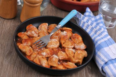 Domates soslu ravioli, parmesan peyniri ve çatal.