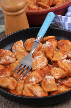 Domates soslu ravioli, parmesan peyniri ve çatal.