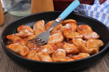 Domates soslu ravioli, parmesan peyniri ve çatal.