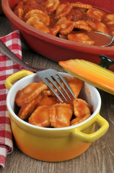 Ravioli güveci masada bir çatalla servis edilir. Yanında da bir tabak mantı.