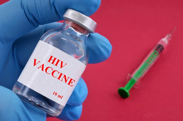 Hivワクチンコンセプトとともにバイアルでラテックス手袋手と注射器上の赤の背景 — ストック写真