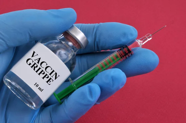 フランスのインフルエンザワクチンコンセプトバイアルと注射器でラテックス手袋をした手で赤の背景 — ストック写真