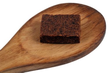 Tahta bir kaşıkta, beyaz arka planda Bouillon küpü. 