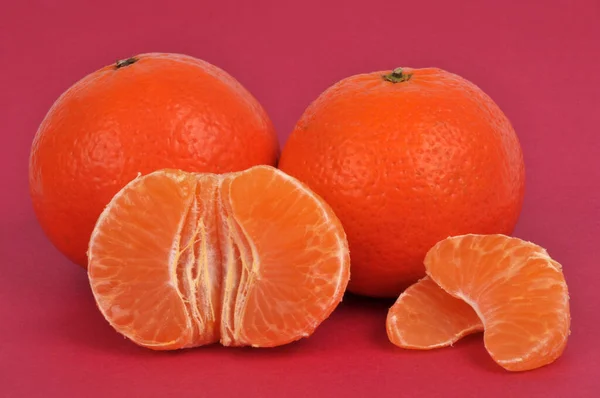 Ganze Mandarinen Und Geschälte Mandarinen Nahaufnahme Auf Rotem Hintergrund — Stockfoto