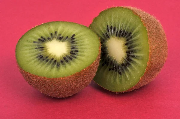 Kiwi Kırmızı Arkaplanda Yarı Yarıya Küçüldü — Stok fotoğraf