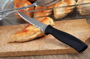 Kesme tahtasının üzerinde tavuk göğsü pişirirken bıçakla tabağın yanında. 