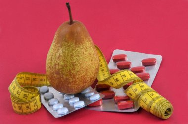 Diyet armudu ve diyet takviyesi kavramı. Kırmızı arka planda esnek sayaç ve ilaç kabarcıkları var.