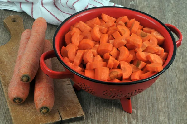 Colador Lleno Zanahorias Cortadas Junto Zanahorias Enteras Una Tabla Cortar — Foto de Stock