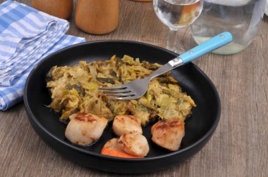 Pırasalı fondü ve çatallı yakın plan deniz tarağı tabağı.