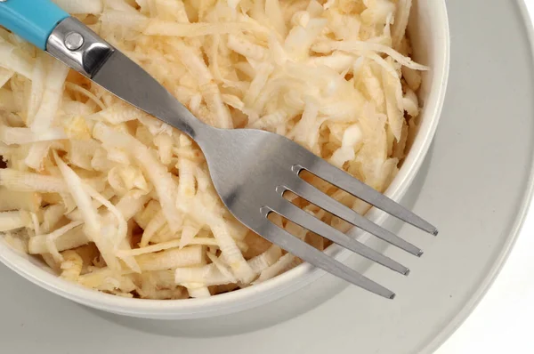 Beyaz arka planda çatallı rendelenmiş kereviz kasesi.