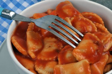 Biftek ravioli ve domates sosu yakın plan çatalla servis edilir.