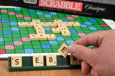 Fransızca bir kelime yapmak için elinde Scrabble mektubu var.