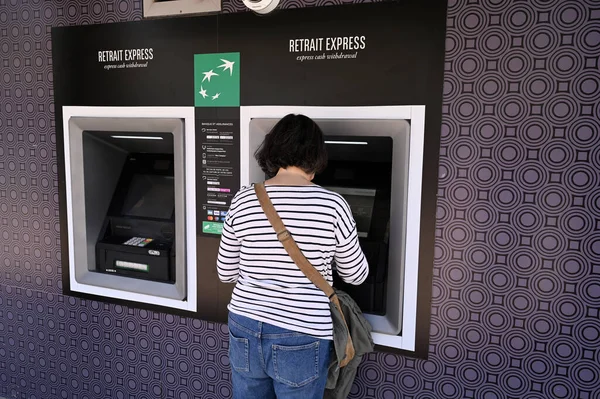 Arkadaki kadın, Paris Ulusal Bankası 'nın ATM' sinden para çekiyor.