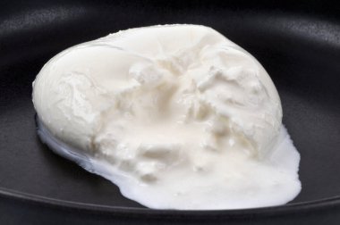 Kremalı burrata di bufala siyah bir tabakta yakın plan. 