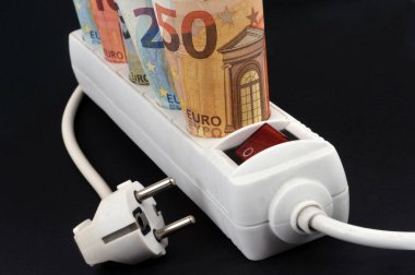 Elektrik uzatma kablosu ve siyah arkaplan üzerine avro banknotları ile elektrik giderleri kavramı