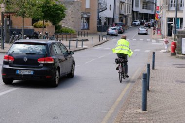 Sarı yelekli ve kasksız bisikletçi Vannes, Brittany 'de bir sokakta 
