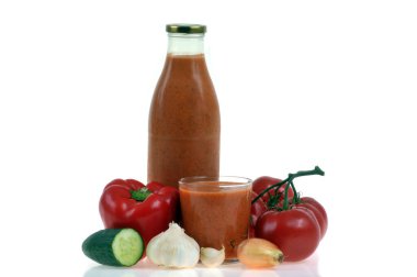 Bir şişe ev yapımı gazpacho ve beyaz arka planda malzemeleri var.
