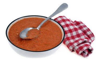 Plate of homemade gazpacho with spoon and napkin on white background