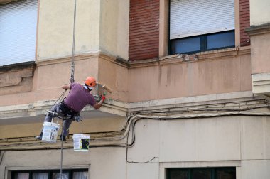 Roped painter working on the facade of a building