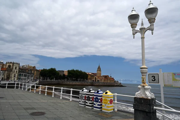 Waste sorting containers for recycling in the city of Gijon in Spain with the San Pedro church in the background