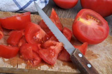 Tomatoes cut into small pieces with a knife on a cutting board close-up