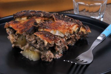 Plate of moussaka with a fork served on a table close-up 